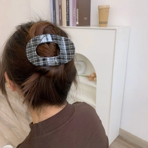 Detail shot of black and white plaid oval hair claw clip securing a brown hair bun