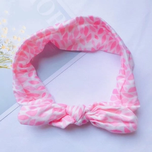 Détail d'un bandeau pour bébé en coton doux à fleurs roses avec un joli nœud torsadé