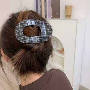 Elegant black and white plaid hair claw clip for women styled on a brunette hair bun
