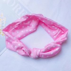 Détail d'un bandeau rose à pois pour bébé en coton doux avec un nœud papillon mignon