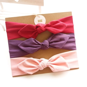 Three-pack cotton baby bow headbands in red, purple, and pink on display card