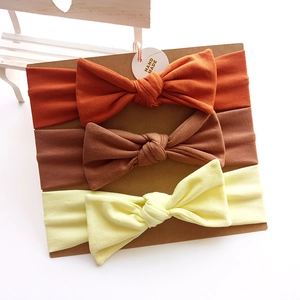 Three-pack cotton baby bow headbands in orange, brown, and yellow on a card