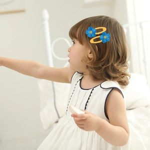 Dettaglio delle mollette per capelli a fiore con paillettes blu e base BB gialla bimba