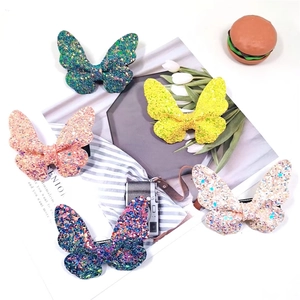 Close-up of glitter butterfly hair clips in green, yellow, pink, and white glitter finishes