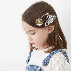 Dettaglio di una bambina con fermagli glitterati con faccina dorata e design argento