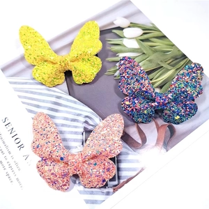 Detailed close-up of glitter butterfly hair clips in yellow, blue and pink colors