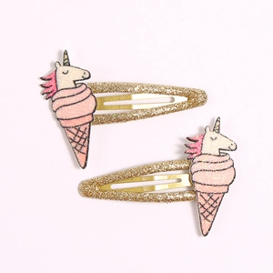 Close-up of glittery unicorn and pink ice cream hair clips with golden sparkle finish