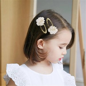 Dettaglio di una bambina con due fermagli dorati con delicate applicazioni di fiori in tulle