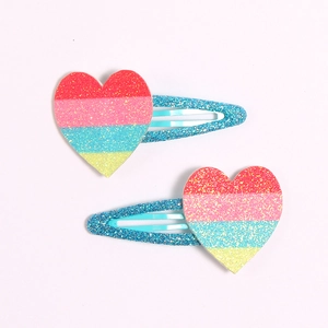 Close-up of glitter heart hair clips with rainbow stripes on blue sequin metal BB clips