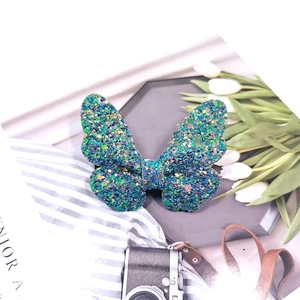 Detail of teal glitter butterfly hair clip on vintage tray with elegant props