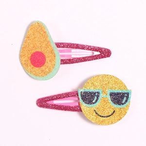 Detail view of glitter avocado and smiley face hair clips for kids on pink snap metal base