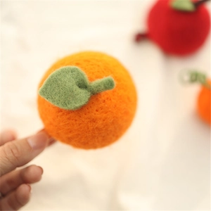 Handmade felt orange hair clip for girls with soft wool texture and green leaf detail
