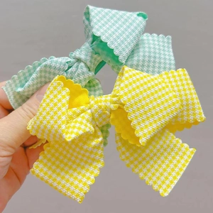 Détail de pinces à cheveux à nœuds quadrillés avec bords festonnés en vert et jaune