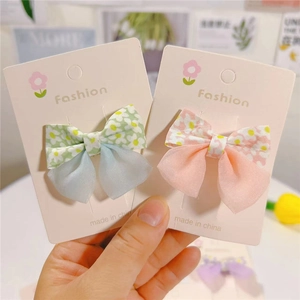 Detail of floral and sheer fabric bow hair clips for girls on display card