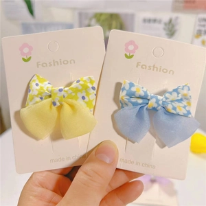 Detailed macro shot of floral print fabric and organza bow hair clips on a card