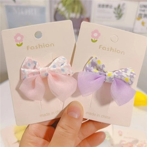 Close-up of pink floral and purple checkered bow hair clips on decorative display card