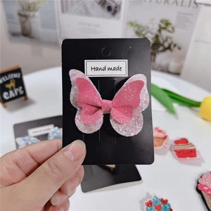 Pince à cheveux papillon pailletée rose et blanche sur carte de présentation