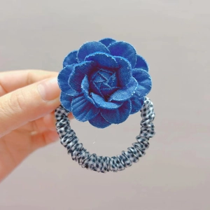 Detalle de un coletero con flor de denim azul y banda elástica de cuadros vichy en blanco y negro