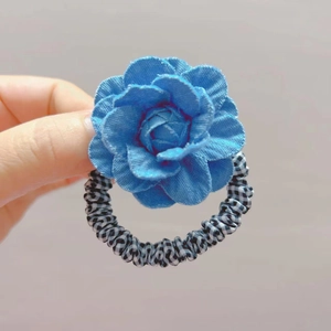 Primer plano de un coletero con flor de camelia azul y elástico con patrón de cuadros blancos y negros