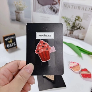 Détail d'une pince à cheveux cupcake rose pailleté avec motif cœur sur support