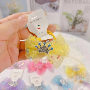Detail of yellow mesh bow hair clip with silver rhinestone crown on branded card