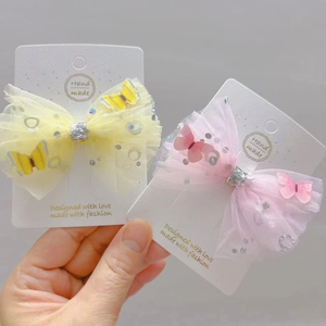 Detail of pink and yellow mesh bow hair clips with sequins on a display card