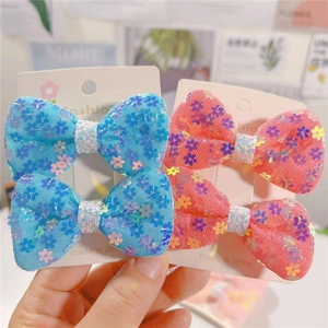 Dettaglio di fermagli per capelli a fiocco con paillettes rosa e blu per bimbe