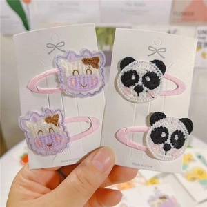 Detail of embroidered cow and panda hair clips on pink fabric covered safety clips
