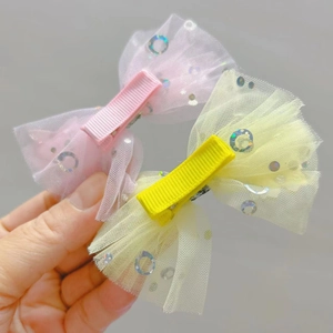 Detail of pink and yellow mesh bow hair clips with sequins and fabric-wrapped alligator clips