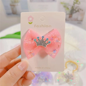 Pink glitter mesh bow hair clip with rhinestone crown detail on a fashion card