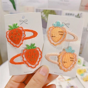 Close-up of embroidered strawberry and carrot hair clips with fabric wrapped edges