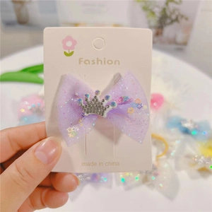 Detailed macro of a purple tulle bow hair clip with a sparkling rhinestone crown ornament