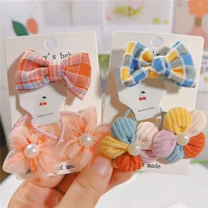 Détail de barrettes nœuds colorées et élastiques fleurs avec perles pour filles