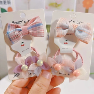 Détail d'élastiques à cheveux avec nœud à carreaux rose et fleur en mousseline pour enfant
