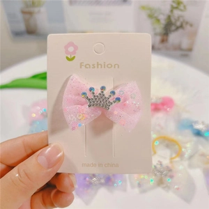 Close-up of pink tulle bow hair clip with silver crown rhinestone detail on display card