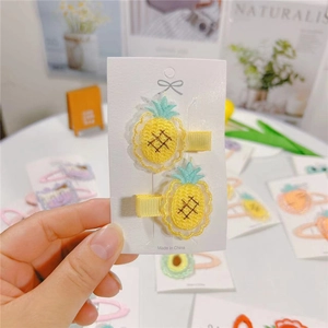 Detail of yellow fabric-wrapped hair clips with cute embroidered pineapple patterns