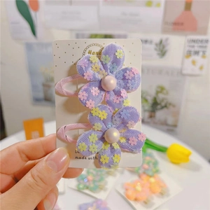 Détail de pinces à cheveux fleurs en maille violette avec paillettes et perles roses