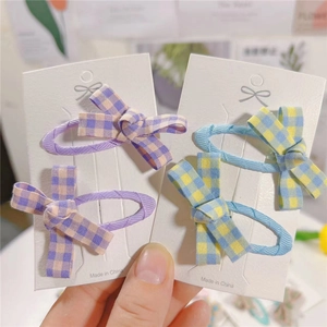 Detailed view of plaid fabric bow hair clips set in purple and blue pastel colors