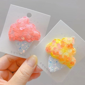 Détail de barrettes à cheveux glace à paillettes roses et jaunes sur carte