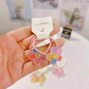 Pink glitter flower hair ties for girls on accessory card shown in hand with cozy background