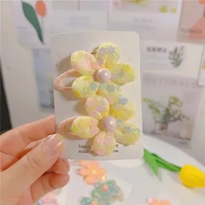 Détail de barrettes fleurs en tissu jaune avec paillettes colorées et perles sur support