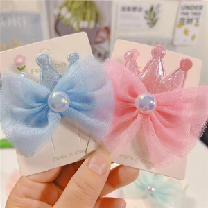 Detail of pink and blue crown hair clips with tulle bows and iridescent pearl accents