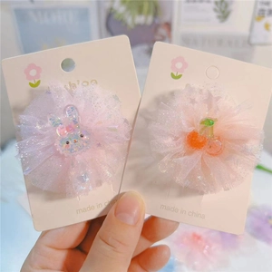 Détail de pinces à cheveux fleurs en tulle rose avec breloques lapin et cerise