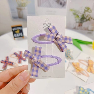 Set of two purple plaid fabric bow hair clips displayed on a white branded card
