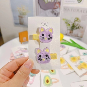 Detail of cute purple embroidered cat hair clips with yellow ribbed fabric wrapping
