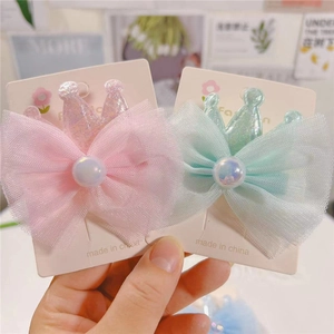 Detail of pink and green mesh bow hair clips with pearlescent crown and pearls