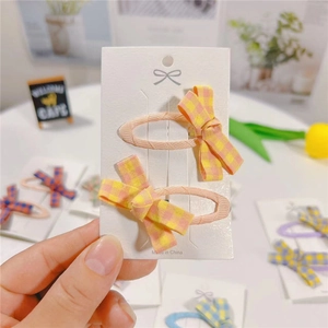 Detail of pink and yellow plaid fabric bow hair clips on white display card
