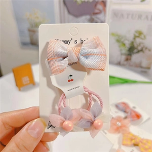 Détail de la pince à cheveux à nœud rose et de l'ensemble de chouchous pour filles