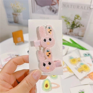 Detailed close-up of pink embroidered bunny hair clips on a white display card