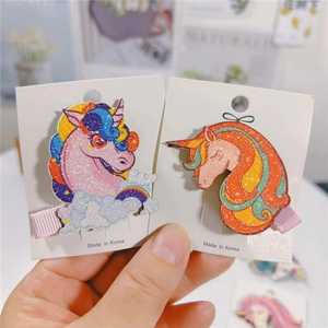 Dettaglio di fermagli per capelli unicorno glitterati con nuvole arcobaleno su carta
